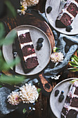 A sliced chocolate and raspberry cake with fresh flowers and berries