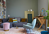 Deep-seat sofa, stool, armchair and wooden bureau in fifties-style living room