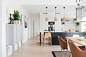 Open-plan kitchen and dining table with classic chairs in bright interior