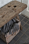 Blanket in wooden crate below old wooden stool