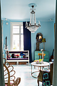 Antike Sitzbank neben Vintage-Kommode in Wohnraum mit blauen Wänden und Kronleuchter