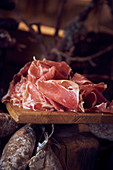 Cured ham, finely sliced, on a wooden board