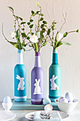 Bemalte und mit Osterhasen dekorierte Flaschen als Vasen