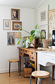 Retro radio and houseplant on two desks below gallery of pictures on wall