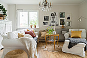 White, loose-covered sofa set and round table in country-house living room