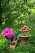 A stack of yeast dough pastries with cherries on a cake stand next to a large bouquet of flowers in a vase