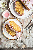 Slices of carrot cake topped with pink icing and chopped pistachios