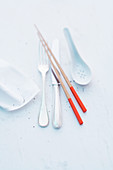 An arrangement of cutlery with chopstick and porcelain spoons