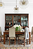 Upholstered chairs with high backs around dining table and antique china cabinet