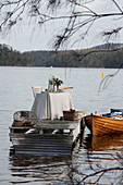 Gedeckter Tisch auf einem Steg und Boot auf einem See