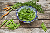 Freshly picked sugar-snap peas and carrots on wooden table