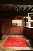 Picture on wall and red rug in simply decorated, renovated Antwerp house