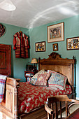 Antique wooden bed in bedroom with turquoise walls in English country house