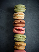 Pile of bright fresh tasty macaron biscuits on grey board and dry fruits