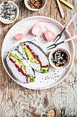 Rainbow vegan onigirazu filled with lettuce, avocado, mango and roasted beetroot
