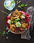 A bowl with beef steak, oyster mushrooms, freekeh, herb cream and radiccio