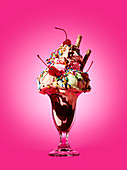 An ice cream sundae against a pink background