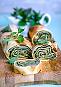 Young nettle strudel, cut into portions on a wooden board, decorated with fresh nettle leaves