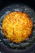 A potato fritter in hot fat