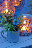 Meadowsweet and love-in-a-mist in mug next to candle lantern