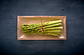A bundle of green asparagus in a wooden dish