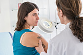Doctor examining tattoo of a woman