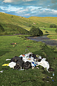 Fly tipping next to a river, Cumbria, UK