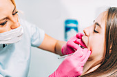 Orthodontist fixing girl's dental braces