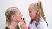 Girl applying lipstick to mother