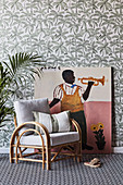 Bamboo chair and large-format mural in front of wallpaper with a plant motif