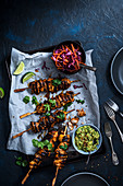 Chicken skewers marinated in garlic, smoked paprika and olive oil with guacamole and cabbage slaw