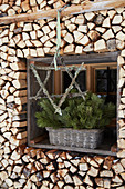 Stern aus Zweigen mit Flechten vorm Fenster im Holzstapel