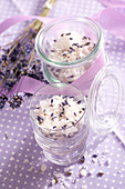 Homemade salt mixtures with lavender flowers in jars on a purple tablecloth