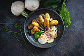 Gebratene Frühkartoffeln, rote Zwiebeln, Mairübchen und Mairübchengrün (vegan)