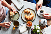 Paar isst Frühstück mit Croissants, Marmelade, Tee und Kaffee