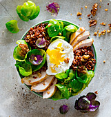Brussels sprouts bowl with red rice, chicken fillets, poached egg and walnuts