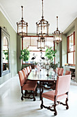 Elegant candlesticks on long dining table and chairs in bright dining room