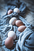 Bunch of chicken eggs lying in tablecloth on rustic wooden table