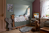 Pale blue cubby bed in child's bedroom with pink walls and vintage desk