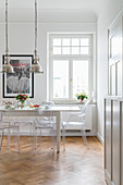 White dining table, Ghost Chairs and silver, industrial-style pendant lamps