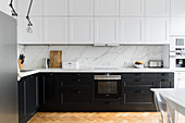 Moderne Küche mit weißen Ober- und schwarzen Unterschränken in Altbauwohnung