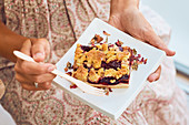 Hands holding sweet tasty granola bar with nuts and dried fruits