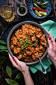 Large bowl of lamb curry on a rustic wood table (India)