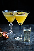 Passion fruit Martini also known as Pornstar Martini in two cocktail glasses decorated with slice of passion fruit with a chaser of Champagne