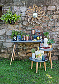 Eklektische Sammlung von Flaschen, Gläsern und Behältern vor Natursteinmauer im Garten