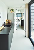 Schwarze Küchenzeile mit Spülbecken im Durchgang zum offenen Wohnbereich