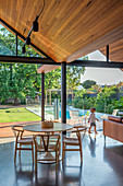 Esstisch in offenem Wohnraum unter Holzspitzdach mit breiten Fensterfronten zum Garten