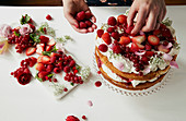Victoria Sponge layer cake being decorated and filled with fresh cream and fruit coulis