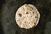 Homemade pita or chapati flatbread flapjack over dark metal background