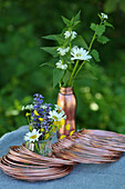 Roll of copper wire and posies of wild summer flowers on table outside